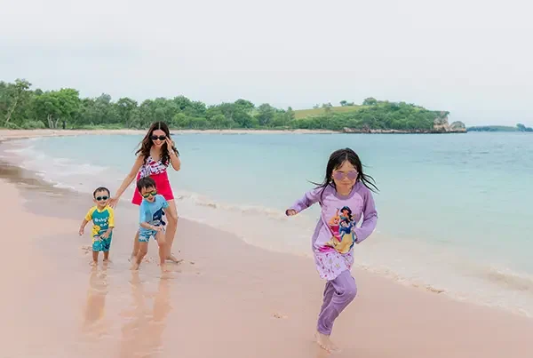 pelanggan paket tour pantai pink lombok berlari di pantai tangsi dengan anak anak